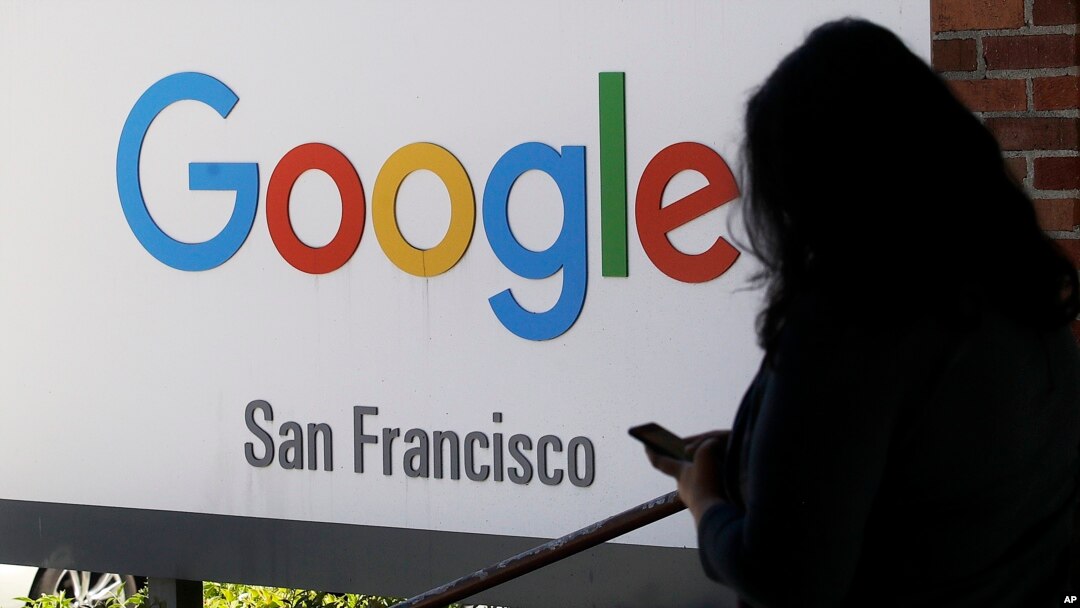 FILE - A person walks past a Google sign in San Francisco, May 1, 2019. 