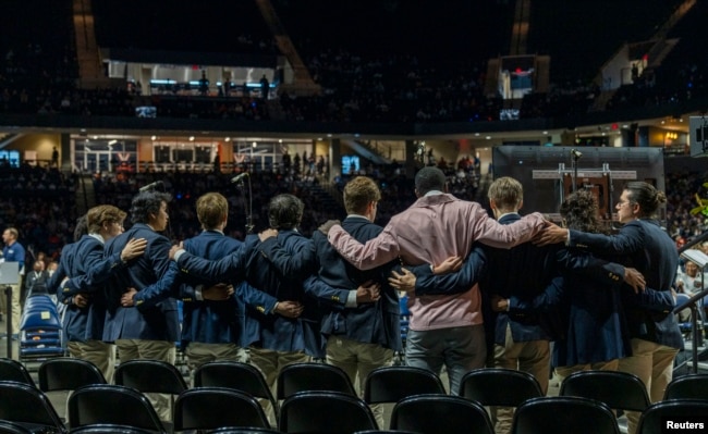 Mourners link arms during a memorial service for three slain University of Virginia football players Lavel Davis Jr., D’Sean Perry and Devin Chandler at John Paul Jones Arena on Nov. 19, 2022. (Erin Edgerton/Pool Photo-USA TODAY Sports via REUTERS)