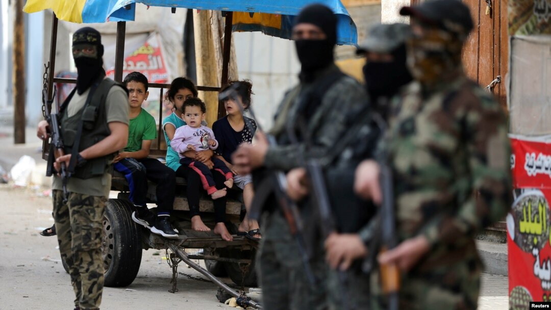 Palestinska deca gledaju u militante Islamskog džihada koji stražare nakon primirja između Izraela i Hamasa, u Gazi, 21. maja 2021. (Foto: Rojters, Ibrahim Abu Mustafa)