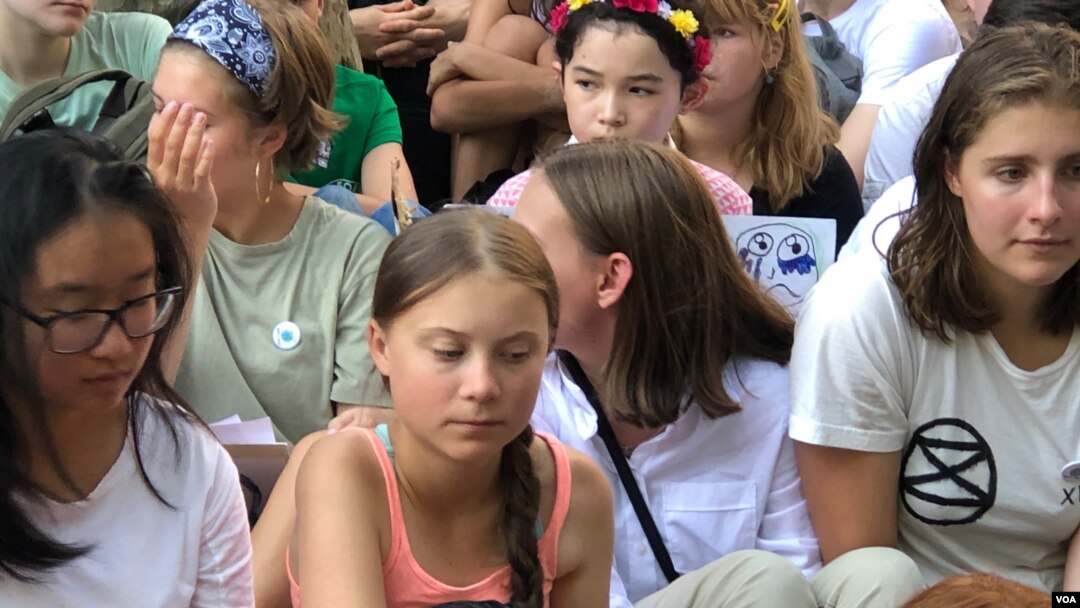 Young climate activist Greta Thunberg, center, listens during a rally outside the United Nations in New York to demand action on global warming, Aug. 30, 2019. (M. Besheer/VOA)