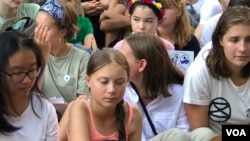 Young climate activist Greta Thunberg, center, listens during a rally outside the United Nations in New York to demand action on global warming, Aug. 30, 2019. (M. Besheer/VOA)