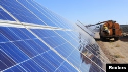 FILE - A worker operates machinery to clean solar panels at a photovoltaic industrial park in Hami, Xinjiang Uyghur Autonomous Region, China, Oct. 22, 2018. 