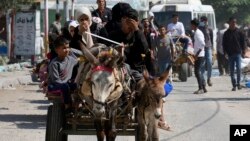 Un grupo de palestinos huyen del norte de Gaza en una carreta tirada por burros para buscar refugio ante la inminente incursión de fuerzas militares israelíes, el viernes 13 de octubre de 2023.