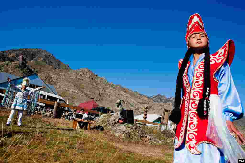 At the Chui Oozi cultural center, a young woman shows off traditional native dress. In the background, Bolot Byiryshev, one of Altai’s most accomplished throat singers, rests after singing an epic ballad. (Vera Undritz for VOA)