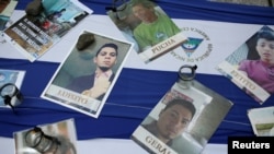 Fotos de personas que perecieron durante las protestas en Nicaragua en 2018 se observan sobre una bandera nicaragüense en una marcha de exiliados en Costa Rica el 7 de noviembre de 2021.