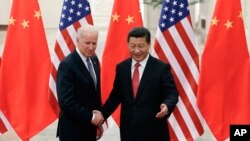 Chinese President Xi Jinping, right, shakes hands with U.S Vice President Joe Biden, left, as they pose for photos at the Great Hall of the People in Beijing, Dec. 4, 2013. 