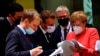 German Chancellor Angela Merkel, right, speaks with French President Emmanuel Macron, center, during a round table meeting at an EU summit in Brussels, Monday, July 20, 2020. Weary European Union leaders are expressing cautious optimism that a deal…