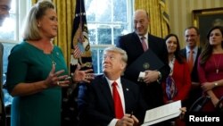 U.S. President Donald Trump looks up at Rep. Ann Wagner after signing an executive order on financial system regulation at the White House in Washington, Feb. 3, 2017. 