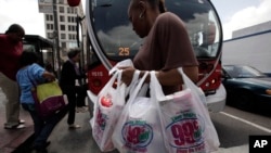 FILE -- A woman carries her purchases in plastic bags in Los Angeles. Plastics discarded by people often end up in the ocean, creating coastal pollution that harms marine life and gathers out at sea in what's become known as the great Pacific garbage patc