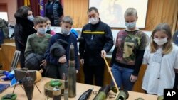 Un agente de la policía muestra explosivos a escolares durante una lección de seguridad organizada por la policía en una escuela de Kiev, Ucrania, el 27 de enero de 2022. Las autoridades de la ciudad están entrenando a civiles en medio de temores de una posible invasión de Rusia.