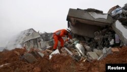 A firefighter uses a flashlight to search for survivors among the debris of collapsed buildings after a landslide hit an industrial park in Shenzhen, Guangzhou, China, Dec. 20, 2015. 