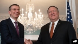 FILE - Secretary of State Mike Pompeo, right, shakes hands with Latvian Foreign Minister Edgars Rinkevics, during a media opportunity at the State Department, in Washington, Feb. 27, 2020.