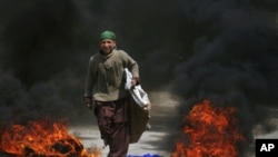 A boy walks past tires set ablaze by protesters following a shootout by unidentified gunmen in Pakistan's southwestern city of Quetta, March 29, 2012. 