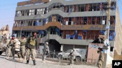 US soldiers and Afghan security forces stand guard at the site of a car bomb in front of a branch of the Kabul bank in Kandahar on 27 Dec 2010