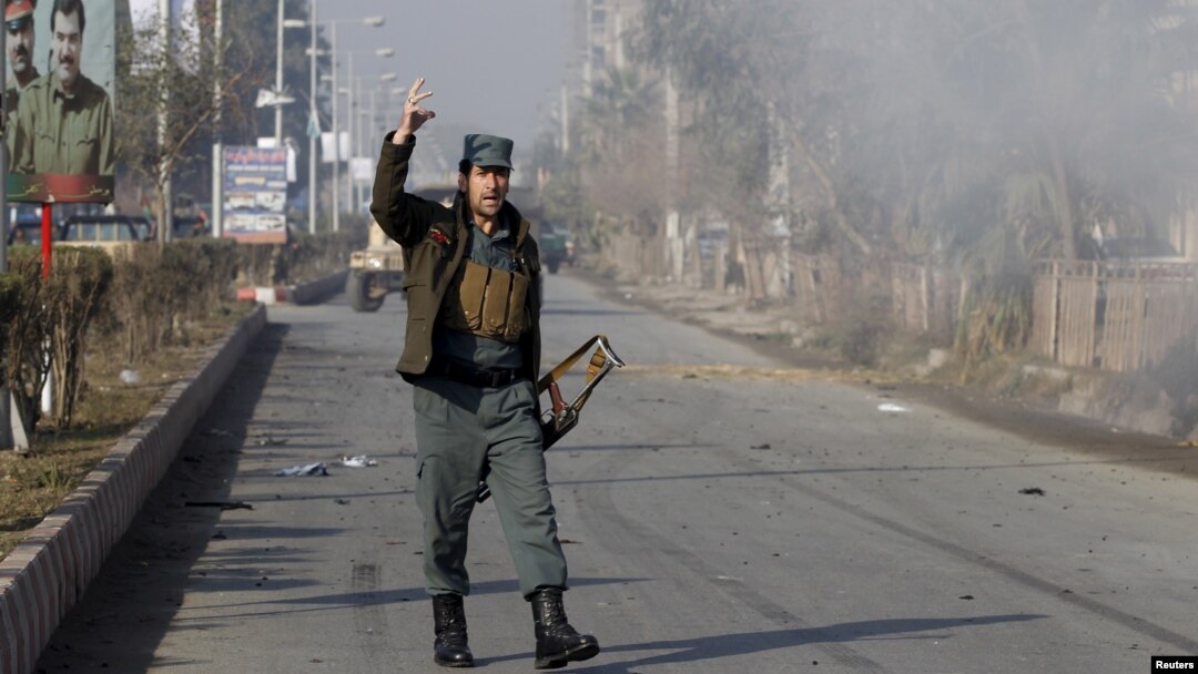 Seorang polisi Afghanistan memberikan komentar saat melihat asap akibat serangan di dekat konsulat Pakistan di Jalalabad, Afghanistan (13/1).
