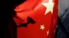 FILE - A surveillance camera is silhouetted behind a Chinese national flag in Beijing, China, Nov. 3, 2022.