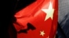 FILE - A surveillance camera is silhouetted behind a Chinese national flag in Beijing. Foreign academics are facing increasing challenges in China, as political sensitivities can trigger harsh reactions from authorities, leading to censorship and suppression of academic freedom.