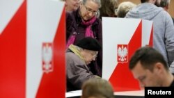 FILE - People attend the Polish regional elections, at a polling station in Warsaw, Poland, Oct. 21, 2018. 