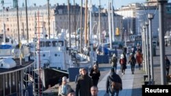 Orang berjalan-jalan dalam cuaca dingin tapi cerah di sepanjang dermaga Standvagen, di tengah penyebaran pandemi Covid-19 yang terus menerus di Stockholm, Swedia, 20 November 2020. (Foto: Reuters)