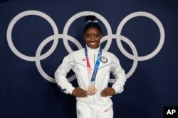 Simone Biles, of the United States, poses wearing her bronze medal from balance beam competition during artistic gymnastics at the 2020 Summer Olympics, Tuesday, Aug. 3, 2021, in Tokyo, Japan. (AP Photo/Natacha Pisarenko)