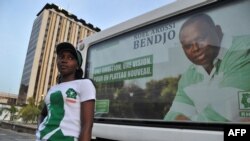 Noël Akossi Bendjo, maire du Plateau, le quartier administratif et des affaires d'Abidjan, sur une affiche devant laquelle se tient une jeune fille, à Abidjan, Côte d’Ivoire, 13 avril 2013.