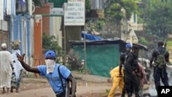 Guinean police carrying automatic weapons clear the mostly Peul suburb of Bambeto in Conakry, Guinea, Tuesday, Nov. 16, 2010, as groups of UFDG youth set up barricades. A de-facto curfew is in effect in the area, residents staying inside, one day after it