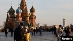 FILE - People wearing face masks to protect against the coronavirus walk across Red Square in Moscow, Russia, Oct. 26, 2021.