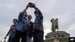 Tourists take photos near the 40-meter-tall stainless steel statue of Genghis Khan, a national hero who amassed power to become the leader of the Mongols in the early 13th century on the outskirts of Ulaanbaatar, Mongolia on July 1, 2024. (AP Photo/Ng Han Guan)