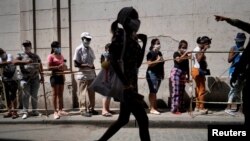 People wait in line to buy food amid concerns about the spread of COVID-19, in downtown Havana, Cuba, April 3, 2020. 