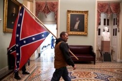 A supporter of President Donald Trump carries a Confederate battle flag on the second floor of the U.S. Capitol after breaching security, in Washington, Jan. 6, 2021.