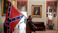 A supporter of President Donald Trump carries a Confederate battle flag on the second floor of the U.S. Capitol after breaching security, in Washington, Jan. 6, 2021.