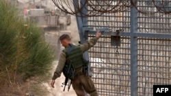 A soldier closes a gate as Israeli military forces cross the fence to and from the buffer zone with Syria, near the Druze village of Majdal Shams in the Israel-annexed Golan Heights, on Dec. 11, 2024.