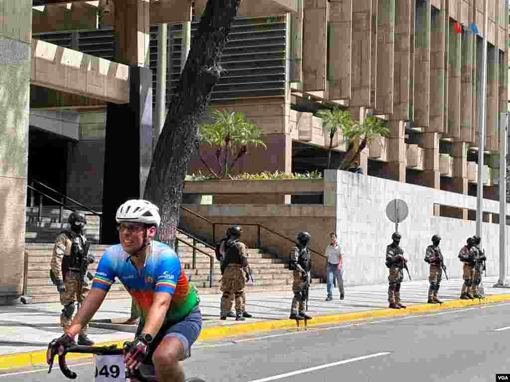 Un ciclista pasa por agentes de seguridad frente a las inmediaciones del Palacio de Miraflores en el centro de Caracas, el viernes 3 de enero de 2025.