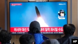 18일 한국 서울역 이용객들이 북한 탄도미사일 발사 TV 뉴스를 시청하고 있다.