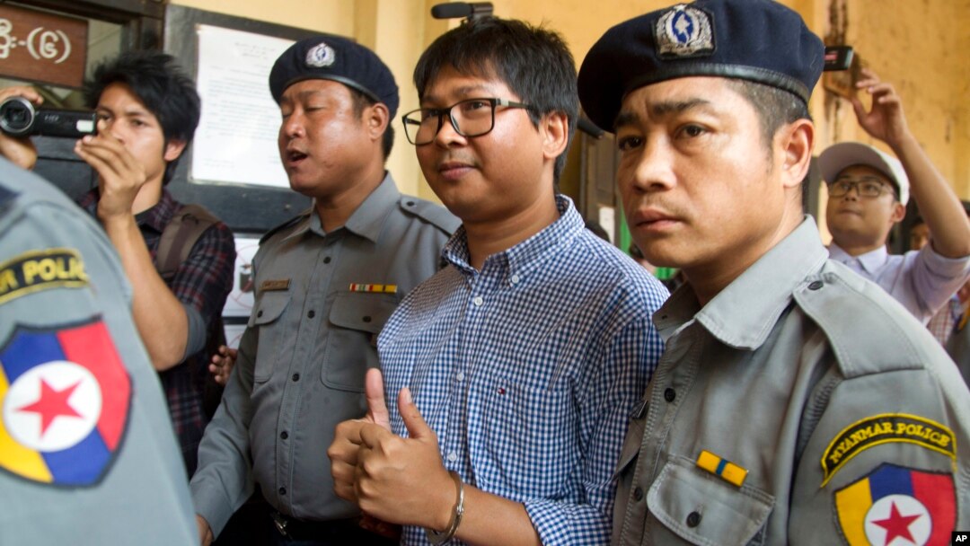Jurnalis Reuters Wa Lone (tengah) mengacungkan dua jempolnya saat dikawal oleh polisi ke pengadilan di Yangon, Myanmar, Kamis (1/2). 