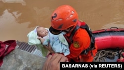  Personel Badan SAR Nasional (Basarnas) mengevakuasi bayi di daerah terdampak banjir di Jakarta, 20 Februari 2021. (Foto: Basarnas via REUTERS)