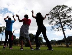 FILE - In this Sept. 24, 2019 photo, girls dance as they do exercises at a shelter for migrant teenage girls, in Lake Worth, Fla.