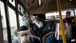 Commuters wearing protective face masks and face shields travel on a public bus in Lima, Peru, July 22, 2020. 