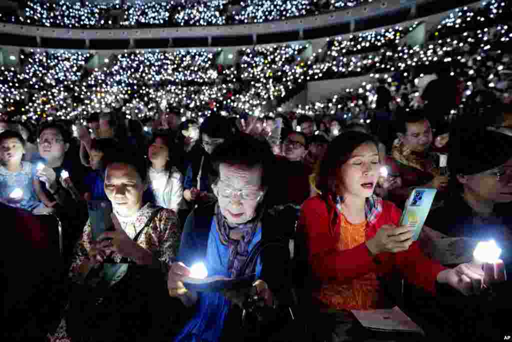 People hold electric candles as they sing during a Christmas Eve service at Indonesia Arena stadium in Jakarta.