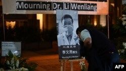 People attend a vigil in Hong Kong for novel coronavirus whistleblowing doctor Li Wenliang, 34, pictured center, who died Friday, Feb. 7, in Wuhan after contracting the virus while treating a patient. 