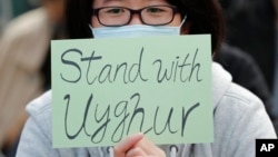 FILE - A man holds a sign during a rally to show support for Uyghurs and their fight for human rights, in Hong Kong, Dec. 22, 2019.