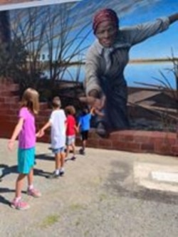 Harriet Tubman reaches out, extending a hand over an unfinished brick wall to draw the viewer into the coastal wetlands beyond. A little girl reached back. Her grandparents posted the image. Soon, it was everywhere. (Courtesy/Downtown Cambridge)