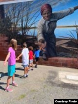 Harriet Tubman reaches out, extending a hand over an unfinished brick wall to draw the viewer into the coastal wetlands beyond. A little girl reached back. Her grandparents posted the image. Soon, it was everywhere. (Courtesy/Downtown Cambridge)