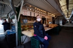 A vendor waits outside her stall at a deserted market in Budapest, Hungary, March 25, 2021.