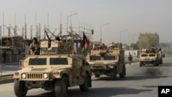 Afghan security personnel leave the area after a battle with Taliban insurgents who took over a building in Kabul, April 16, 2012.