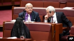 Sen. Pauline Hanson, bottom left, wears a burqa during question time in the Senate chamber at Parliament House in Canberra, Australia, Aug. 17, 2017.