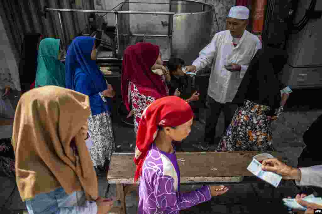 Warga antre menerima sumbangan uang menjelang Idul Fitri di Surabaya, 31 Mei 2019. (Foto: AFP)