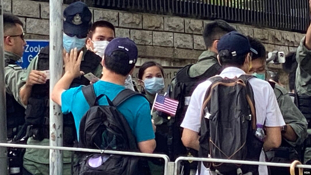 香港市民李先生手持小型的紙製美國國旗，與多名朋友7月4日下午到美國駐港總領事館附近慶祝美國國慶，他們被大批警員截查。(美國之音 湯惠芸拍攝)