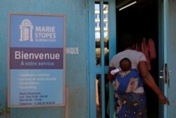 FILE - A woman carrying a baby arrives at the clinic of the NGO Marie Stopes in Ouagadougou, Burkina Faso, Feb. 16, 2018.