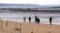 FILE - A family strolls the beaches with shores are lined with iron staves and the land's edge lined with mines, on Taiwan's Kinmen Island, 1.2 miles off China's south east coast, Dec. 13, 2001.